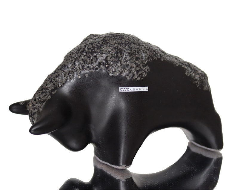 May include: Black ceramic bull figurine with a textured surface. The figurine is made by Otto Keramik.