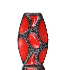 May include: A red and black ceramic vase with a unique geometric pattern. The vase is shaped like a tall, narrow cylinder with a rounded bottom.