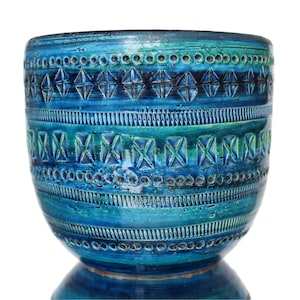 Op de afbeelding: Een blauwe keramische plantenpot met een geometrisch patroon. De pot heeft een brede opening en een ronde basis.