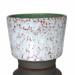 Könnte beinhalten: Ein Set aus drei Keramikbechern mit gesprenkelter, matter Oberfläche. Die Becher sind in den Farbtönen Creme, Hellgrau und Dunkelgrau gehalten. Jeder Becher hat ein schlichtes, minimalistisches Design, ideal für Kaffee oder Tee.