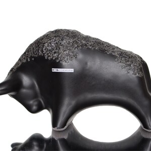 May include: Black ceramic bull sculpture with a textured surface. The sculpture is signed "Otto Keramik" on the side.