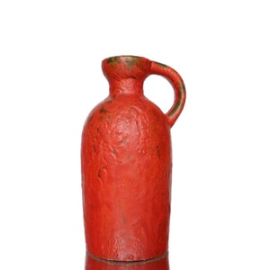 Può includere: Un vaso in ceramica rosso con una superficie testurizzata e un manico. Il vaso è un design classico con una forma semplice ed elegante.