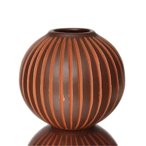 May include: A brown ceramic vase with a ribbed design. The ribs are a lighter shade of orange.