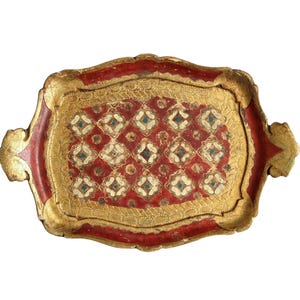 Può includere: Un vassoio da portata antico di forma rettangolare con bordi dorati ornati. Il vassoio presenta uno sfondo rosso con un motivo floreale ripetuto in bianco e turchese. I bordi sono rossi con accenti dorati.