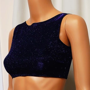 Puede incluir: Un top corto azul oscuro con textura brillante. El top tiene un escote redondo y es sin mangas.