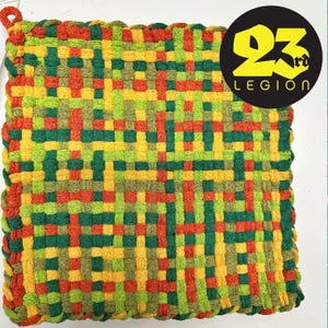 May include: A woven pot holder with a square shape and a fringe border. The pot holder is made with green, yellow, orange, and red yarn.