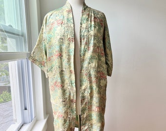 Könnte beinhalten: Eine lange, hellgrüne Seidenrobe mit einem Blumenmuster. Die Robe hat einen Schalkragen und Dreiviertelärmel. Die Robe befindet sich auf einer Holzpuppe.