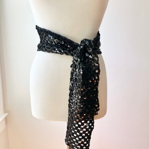 May include: A black sequined belt with a long, flowing tail. The belt is tied in a bow at the front.