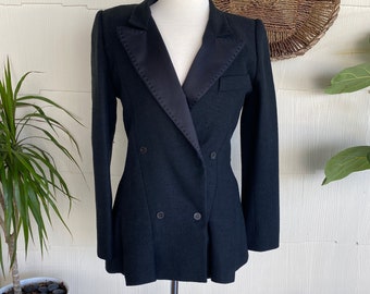 May include: A black blazer with a satin lapel and double breasted closure. The blazer has a fitted silhouette and long sleeves.