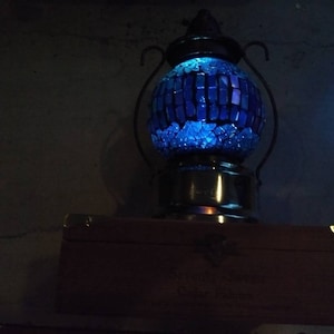 May include: A blue mosaic glass lamp with a metal base and a wooden box underneath.