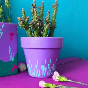May include: A white ceramic mug with a black handle and the text "But First, Coffee" in a black, bold font. The mug is on a wooden surface. The mug is 10 cm tall.