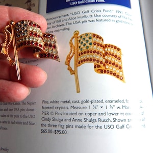 May include: Two gold-plated flag pins with red, white, and blue faceted crystals. The pins measure 1.75 inches by 1.375 inches. The pins are from the USO Gulf Crisis Fund.