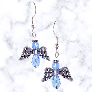 Pu&ograve; includere: Un paio di orecchini pendenti a forma di angelo in argento con accenti di cristallo blu chiaro.