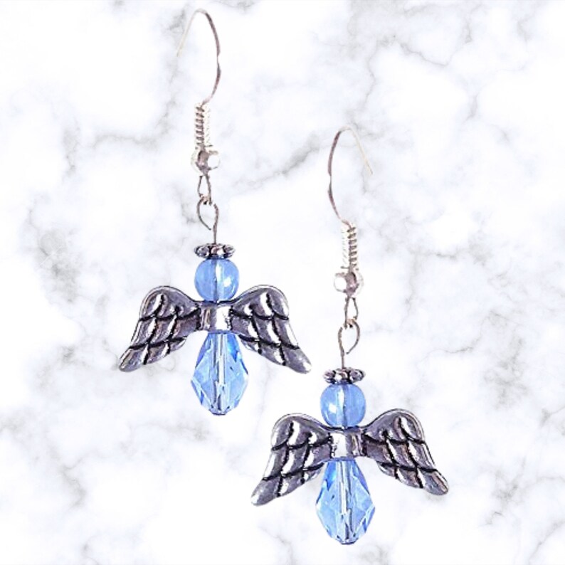 Pu&ograve; includere: Un paio di orecchini pendenti a forma di angelo in argento con accenti di cristallo blu chiaro.