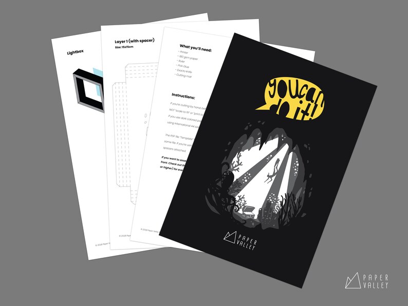 May include: A black and white papercraft design with the words "You can do it!" in a yellow speech bubble. The design features an underwater scene with an octopus, coral, and a diver. The design is from Paper Valley.