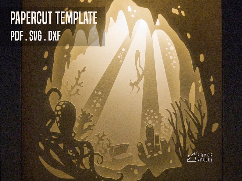 May include: A papercut template of a diver swimming through a cave with an octopus and coral reef. The template is for a light box and includes the text "PAPERCUT TEMPLATE PDF. SVG. DXF" and the logo "PAPER VALLEY".