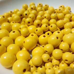 May include: A large bowl filled with bright yellow wooden beads. The beads are round and smooth, and they are all the same size.