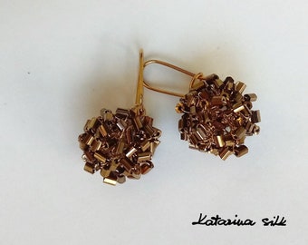 May include: A pair of gold earrings with brown beaded clusters. The earrings are made by Katarina Silk.