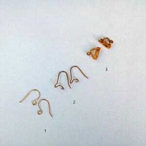 May include: Three different types of earring findings, including two pairs of gold-toned ear wires and a pair of gold-toned clip-on earring backs.