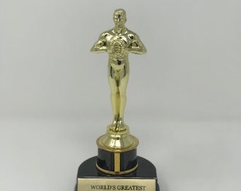 May include: Gold-colored trophy with a black base. The trophy features a figurine of a person holding a star. The base has the text "World's Greatest Sister".