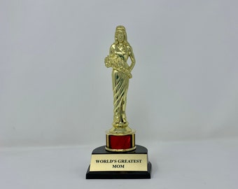 May include: Gold-colored trophy with a female figure holding a bouquet of flowers. The base is black with a red band and the words "WORLD'S GREATEST MOM" inscribed on the front.