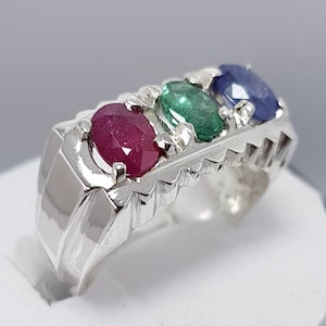 May include: A silver ring with three oval-shaped gemstones. The gemstones are red, green, and blue.