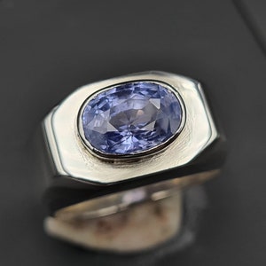 May include: A silver ring featuring a light blue oval sapphire gemstone.