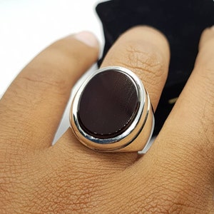 May include: A silver ring with a large, oval-shaped, dark brown gemstone.