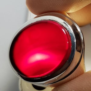 May include: A silver ring with a large, round, red gemstone set in the center.