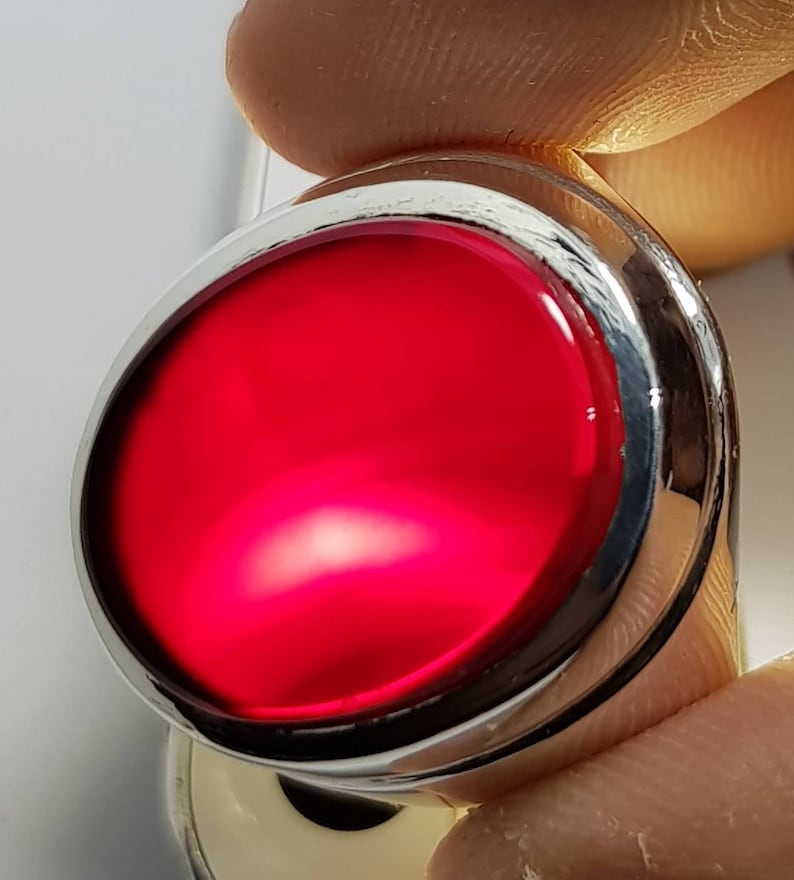 May include: A silver ring with a large, round, red gemstone set in the center.