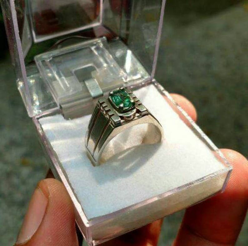 May include: A silver ring with a green gemstone set in a decorative band.