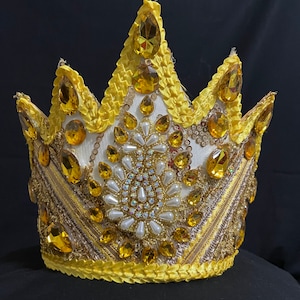 Puede incluir: Una corona amarilla con adornos dorados y blancos. La corona est&aacute; decorada con joyas transparentes y &aacute;mbar.