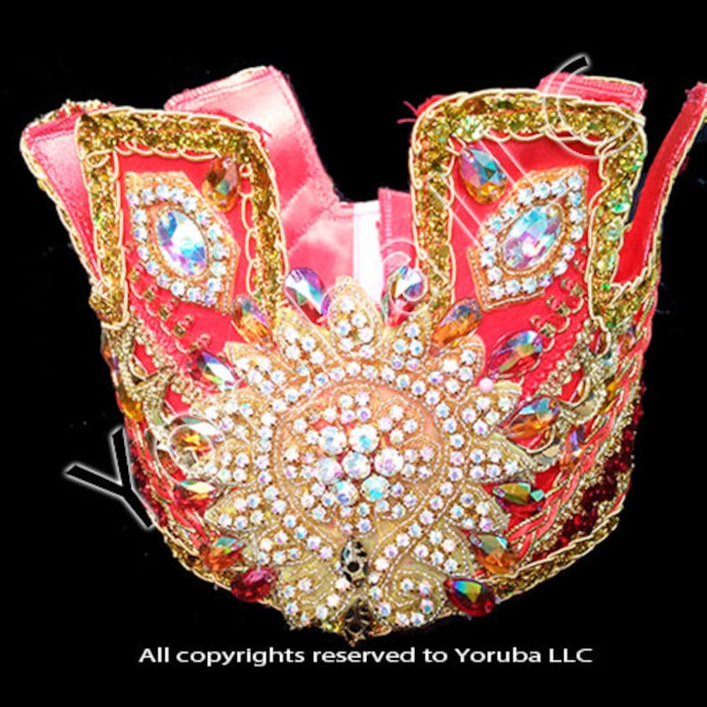 Puede incluir: Una corona roja y dorada con una gran pieza central adornada con joyas brillantes. La corona est&aacute; decorada con joyas m&aacute;s peque&ntilde;as y ribetes dorados.