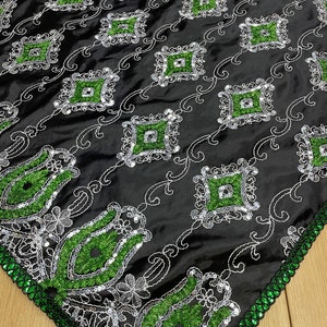 May include: Black fabric with green and silver sequins in a diamond pattern. The fabric has a decorative border with green and black sequins.