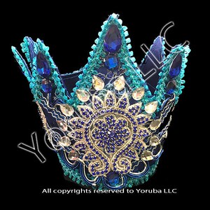 Puede incluir: Una corona azul y turquesa con un dise&ntilde;o floral dorado y azul y diamantes de imitaci&oacute;n azules. La corona est&aacute; hecha de tela y est&aacute; decorada con lentejuelas y cuentas.