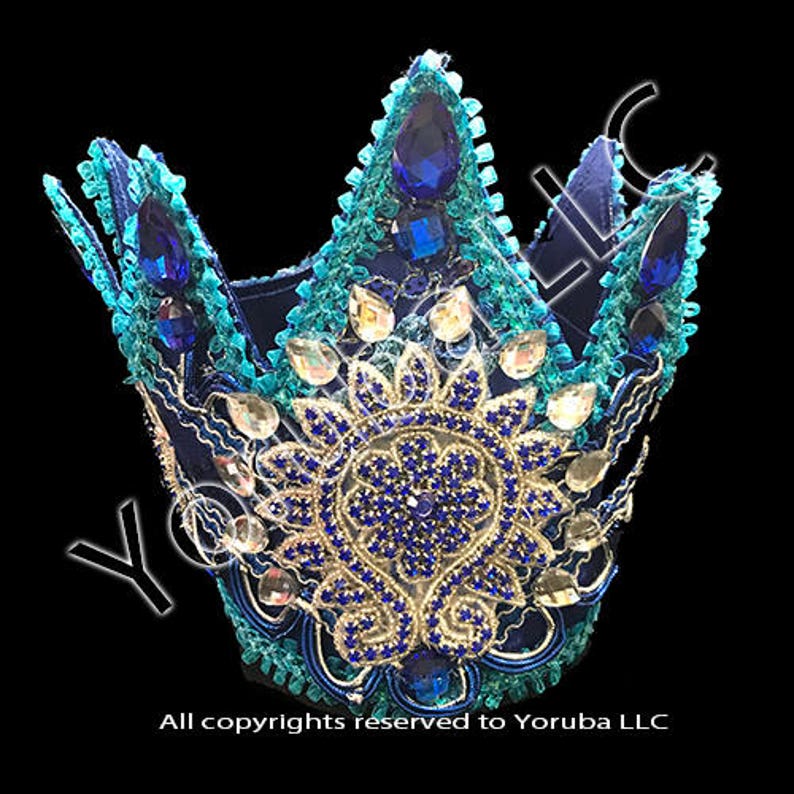 Puede incluir: Una corona azul y turquesa con un dise&ntilde;o floral dorado y azul y diamantes de imitaci&oacute;n azules. La corona est&aacute; hecha de tela y est&aacute; decorada con lentejuelas y cuentas.