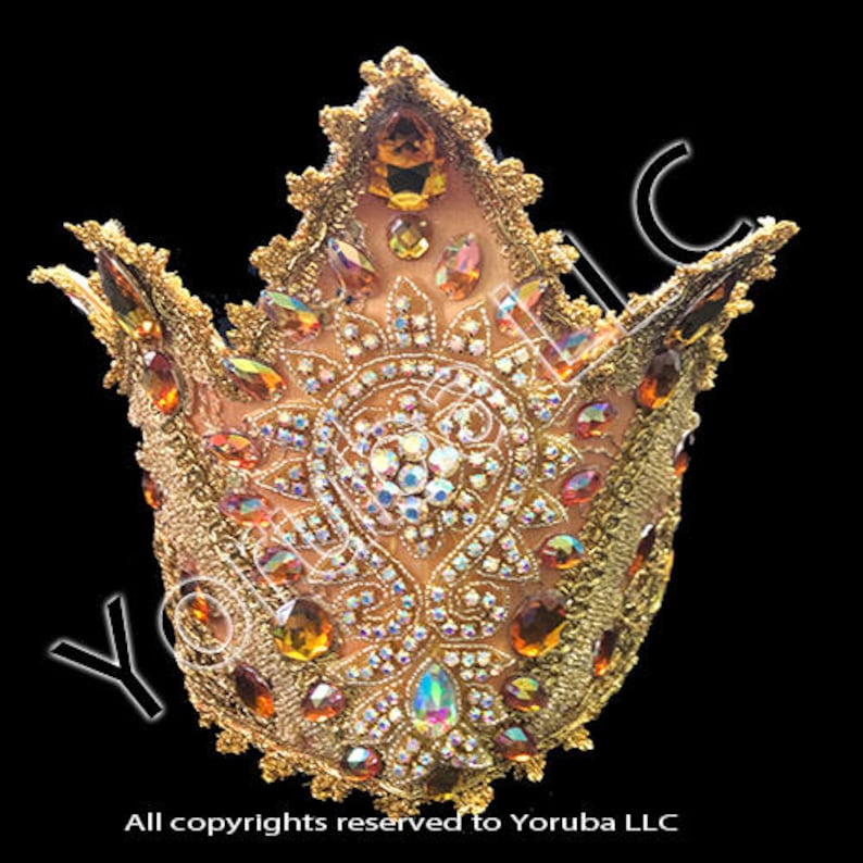 Puede incluir: Una corona dorada con una parte superior puntiaguda y detalles intrincados. La corona est&aacute; decorada con diamantes de imitaci&oacute;n y joyas de color &aacute;mbar.