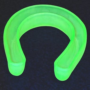 May include: A neon green, U-shaped object with a rounded design. The object appears to be made of a translucent material, with a smooth, curved surface. The object is set against a dark background.
