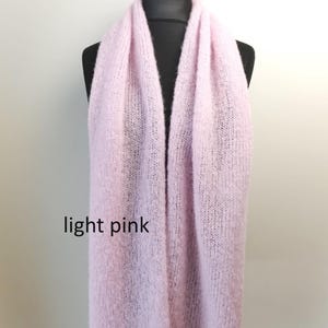 May include: A light pink scarf displayed on a black mannequin. The scarf is made of a soft, knitted material. The text "light pink" is visible on the bottom left of the image. The scarf is a solid color and appears to be a winter accessory.