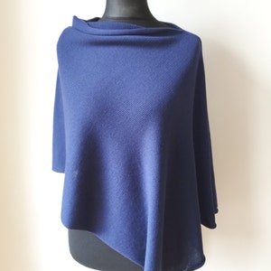 Könnte beinhalten: Ein marineblauer Strickponcho mit Rippenstruktur. Der Poncho ist über eine Schaufensterpuppe gelegt.