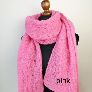 May include: A bright pink, fluffy scarf draped over a mannequin. The scarf is made of a soft, textured material and is a vibrant shade of pink. The word "pink" is written on the scarf in black text.
