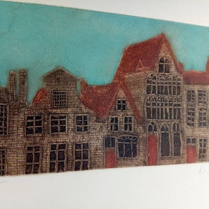 May include: A vintage etching of a row of buildings with a blue sky in the background. The buildings are brown and have windows and doors. The etching is numbered 35/45.