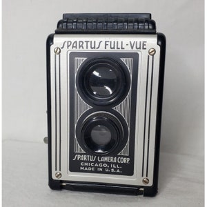 Könnte beinhalten: Eine vintage Spartus Full-Vue Kamera in Schwarz und Silber mit zwei Objektiven. Die Kamera trägt den Text "SPARTUS FULL-VUE" und "SPARTUS CAMERA CORP. CHICAGO, ILL. MADE IN U.S.A."