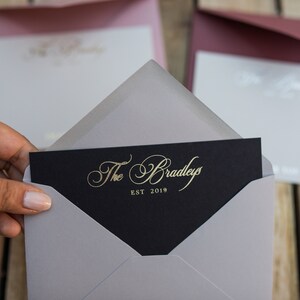 May include: A gray envelope with a black card inside. The card has gold lettering that reads "The Bradleys EST 2019".