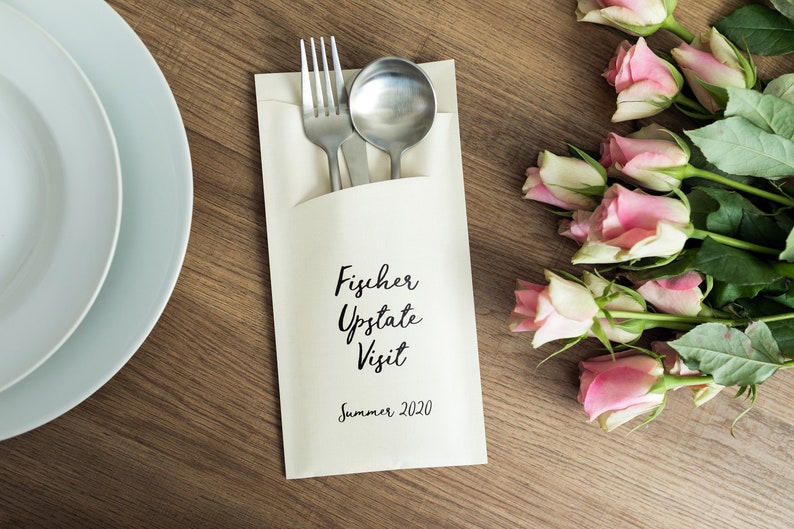 May include: A white paper napkin with a silver fork and spoon inside. The napkin has the text "Fischer Upstate Visit Summer 2020" printed on it.