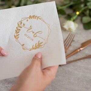 Pu&ograve; includere: Tovagliolo di carta bianco con un design in foglia d'oro di una cornice geometrica con rami frondosi e le iniziali "r & b" e la data "10.27.18".