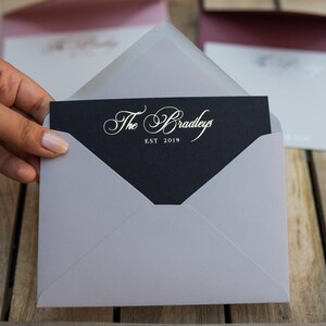 May include: A gray envelope with a black card inside. The card has gold lettering that reads "The Bradleys EST 2019".