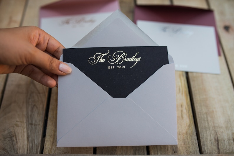 May include: A gray envelope with a black card inside. The card has gold lettering that reads "The Bradleys EST 2019".