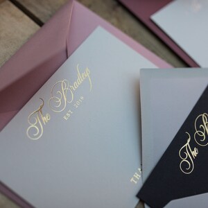 May include: Two envelopes with a light gray and black background. The envelopes have a gold foil design with the text "The Bradley Est 2019".