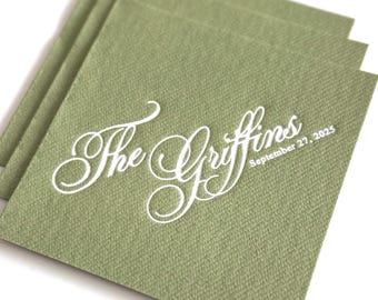 May include: A stack of square, sage green paper napkins featuring white printed text. The text displays the phrase The Griffins in a large, elegant script font, followed by the date September 27, 2025, in a smaller, clean sans-serif font.